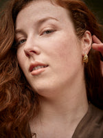Front view of a woman wearing a gold-colored earring