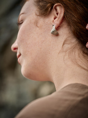 
                  
                    Upload image to gallery, Woman holding her hair to reveal a textured silver earring
                  
                