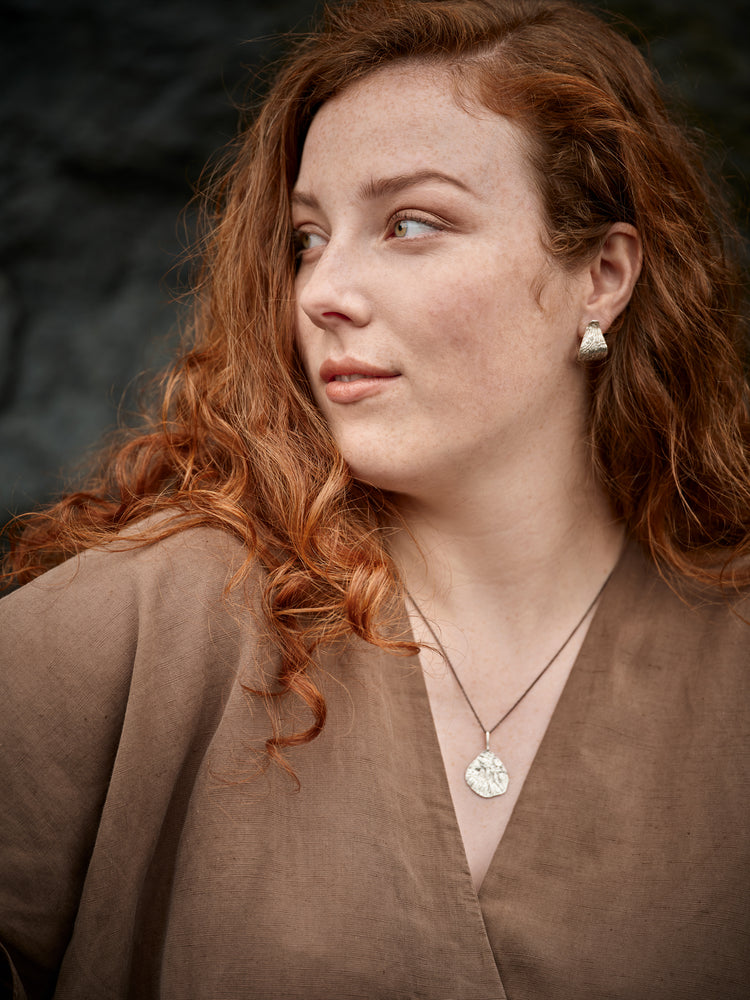 Portrait of a woman wearing a silver necklace and silver earrings