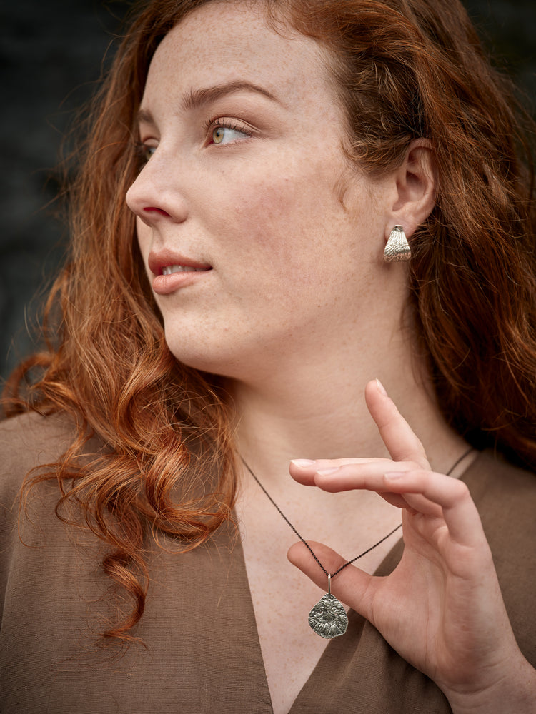 Woman in profile wearing a silver earring and necklace