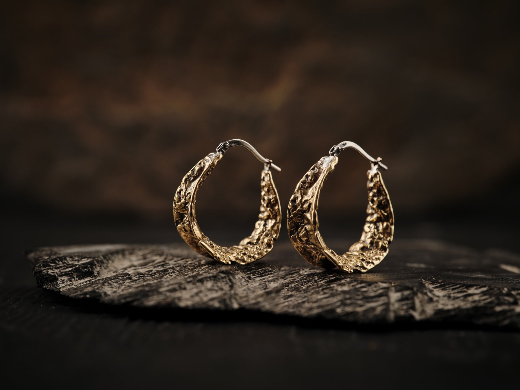 Anneaux d'oreilles texturées en laiton possédant un fermoir de type dormeuse en argent.
