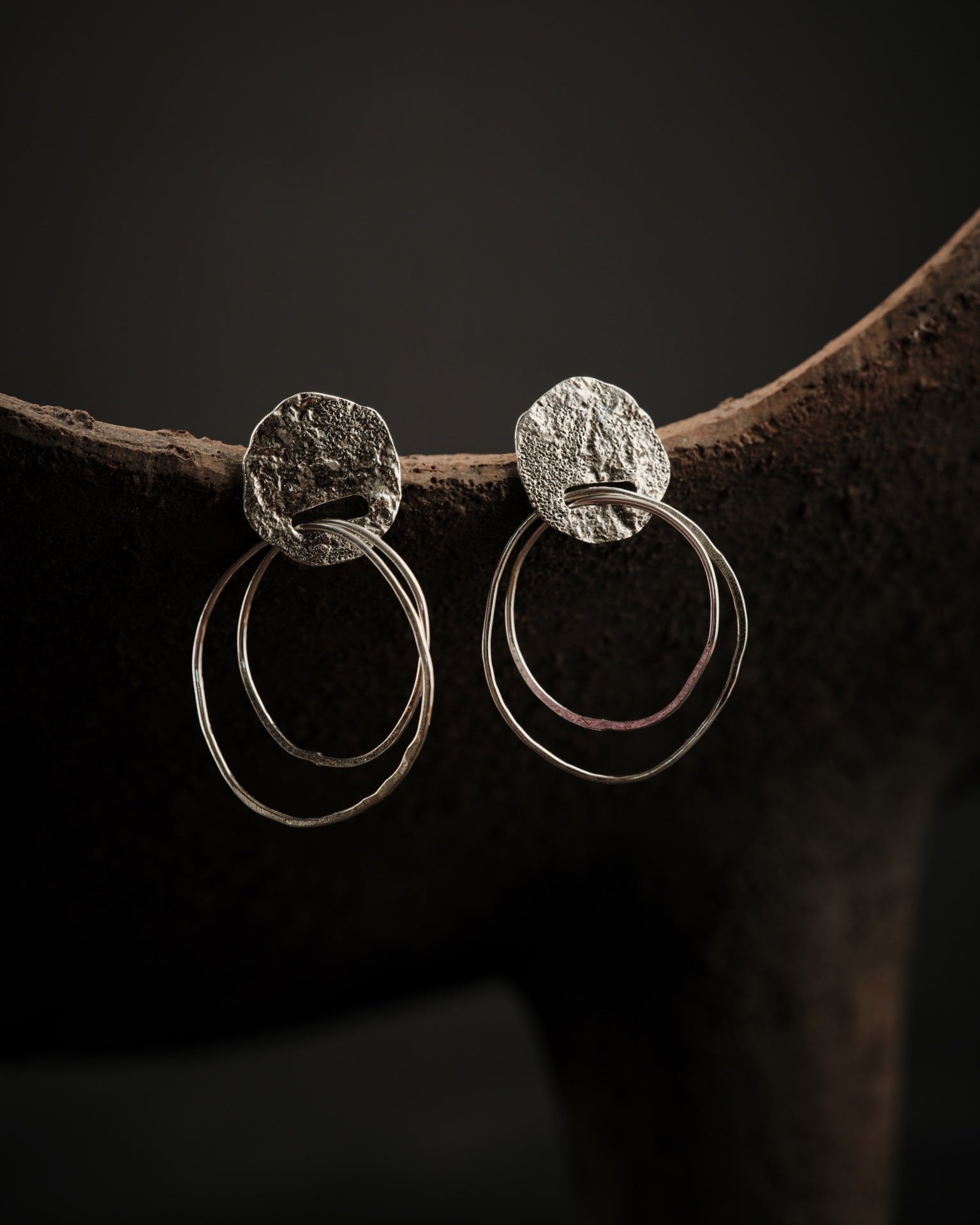 Boucles d'oreilles en argent formées d'une partie supérieur texturée et ajourée dans laquelle s'insère deux petits anneaux d'argent