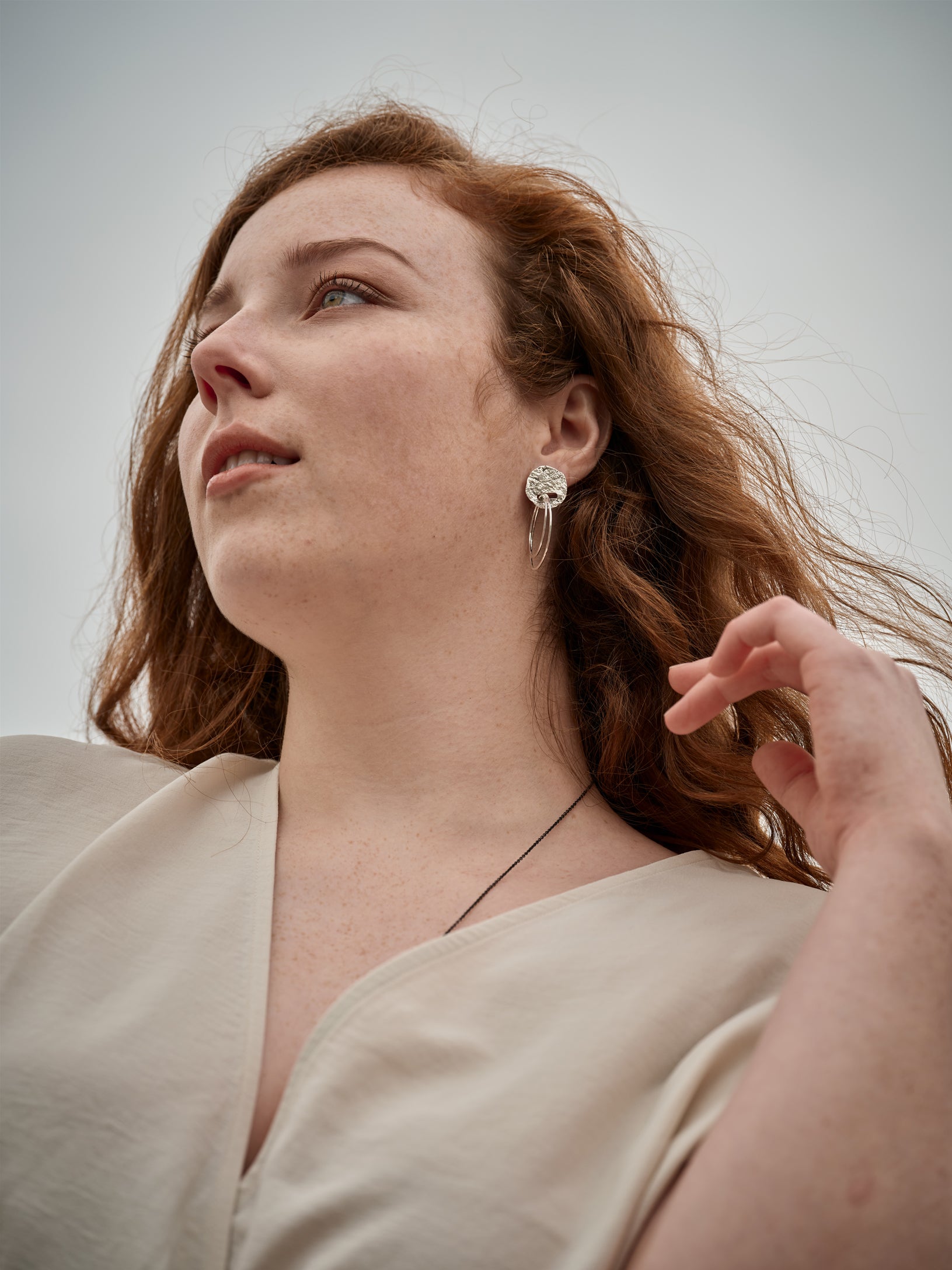 Femme vu en contre plongée portant une boucles d'oreille en argent